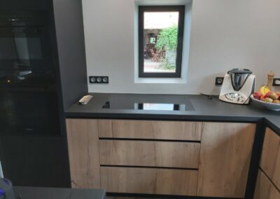 Cuisine avec portes en mélaminé décor bois structuré, dessus en céramique et caissons laqués noirs