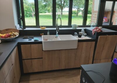 Cuisine avec portes en mélaminé décor bois structuré, dessus en céramique et caissons laqués noirs